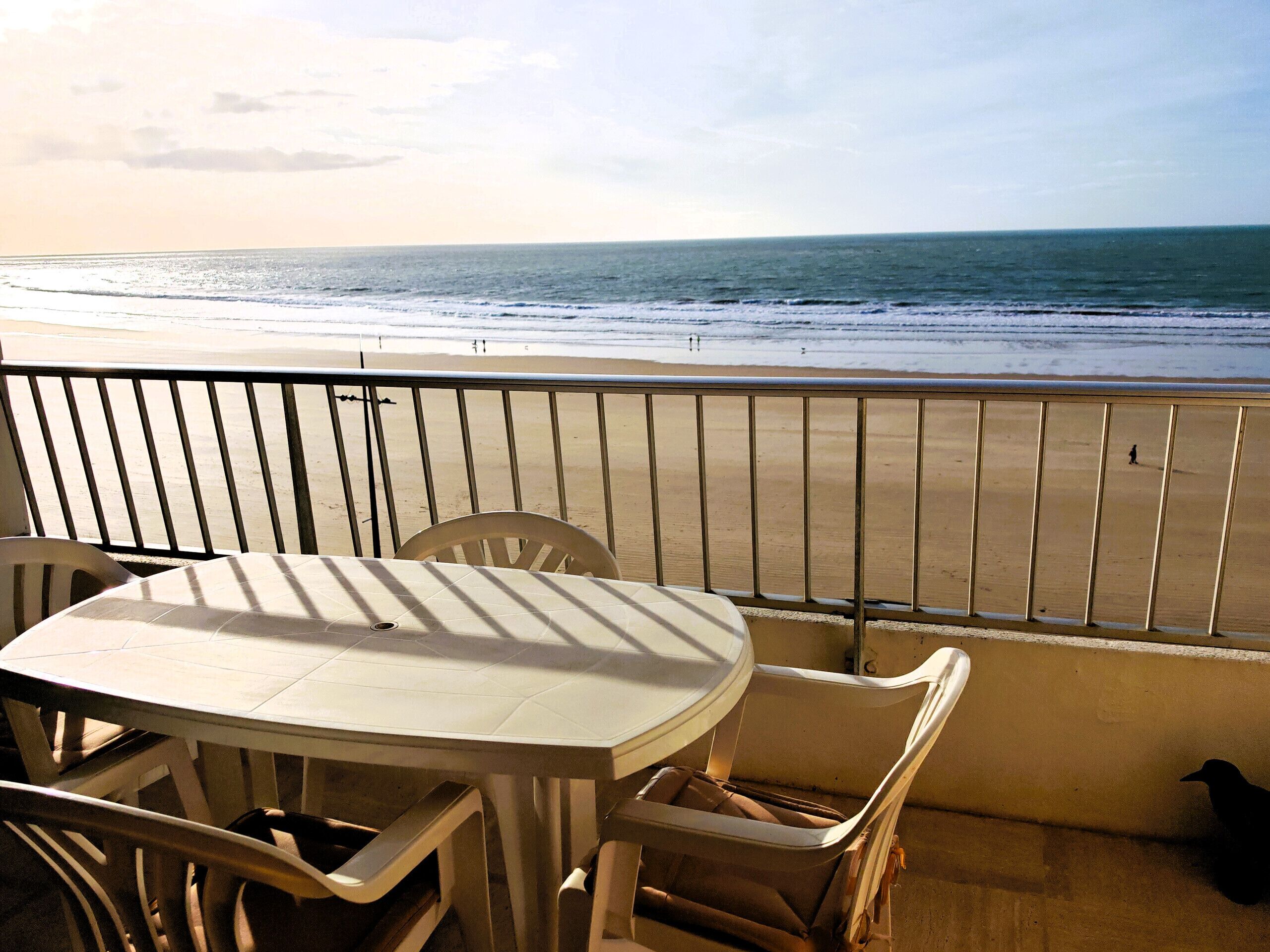 Un balcón con mesa y sillas con vistas a la playa.