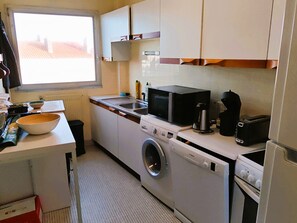 A compact kitchen with a washing machine, microwave, toaster, and a window providing natural light. - THE NEST OF THE BACKFILL - Facing Grande Plage (Les Sables-d´Olonne)