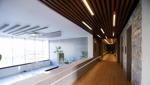 Un hall d’entrée moderne avec un plafond en bois, un comptoir d’accueil agrémenté de plantes et un mur en pierre.