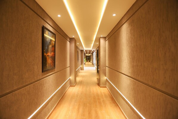 A long, well-lit hallway with wooden walls and a tiled floor, leading to a distant room.