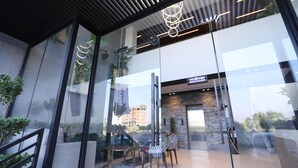 L’entrée d’un hôtel moderne, avec une façade en verre, un mur en pierre et un comptoir d’accueil.