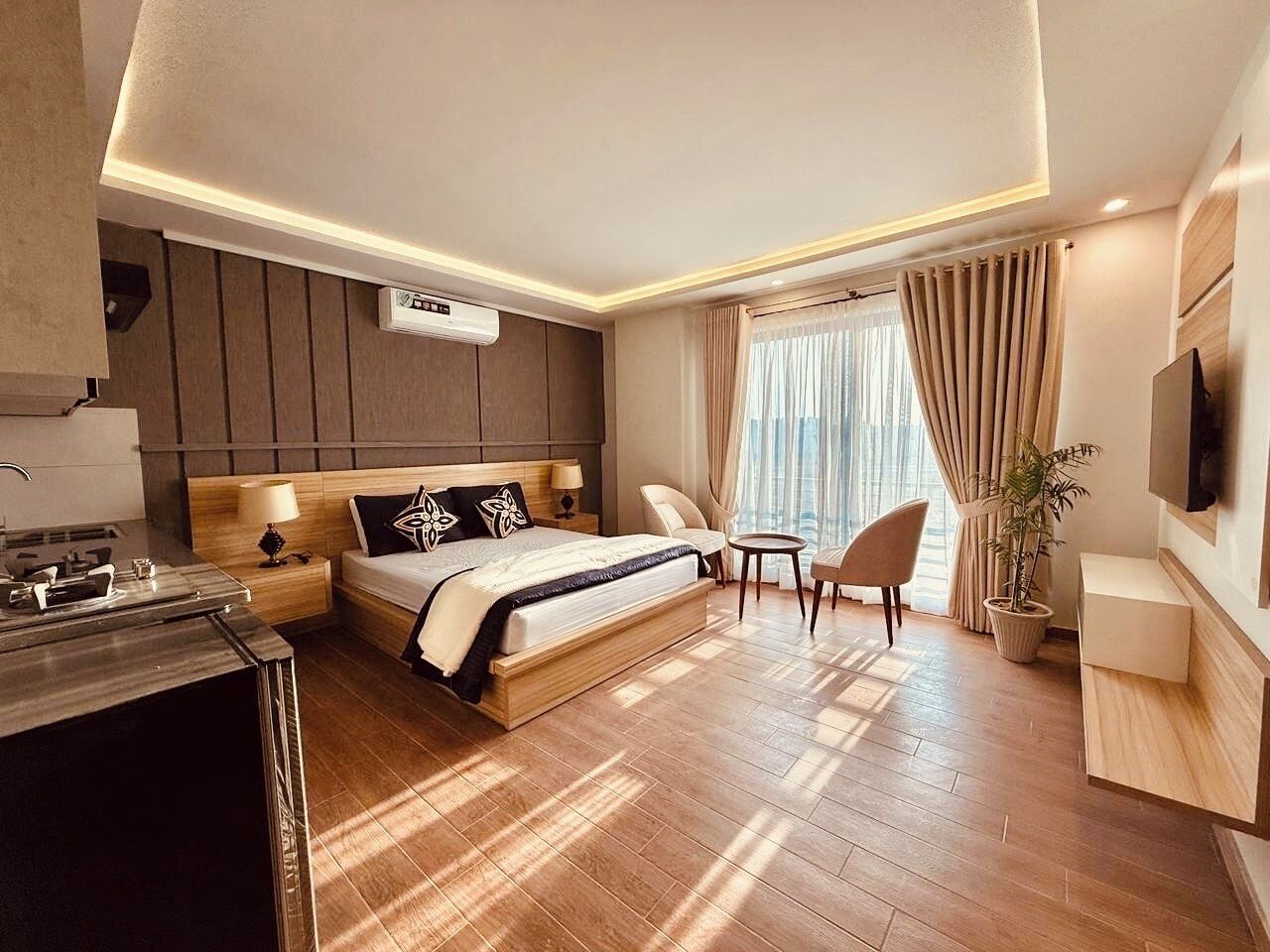 Una habitación de hotel moderna con una cama grande, un escritorio, una silla, un televisor y una planta en maceta.