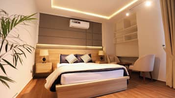 Una habitació d'hotel moderna amb un llit gran, taules de nit, una cadira, una taula petita i una columna d'emmagatzematge integrada.