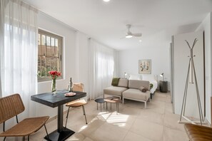 Un salon moderne comprenant un canapé, une table à manger avec des chaises, une lampe sur pied et une lampe de sol.