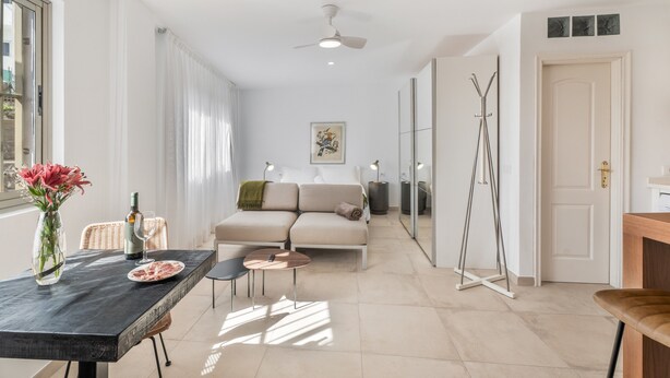 A modern interior with a dining table, sofa, and a mirror.