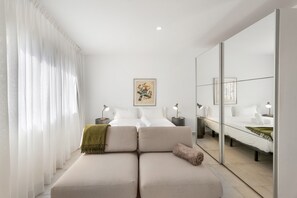 A modern hotel room with a sofa, two beds, a large mirror, and artwork on the wall. - Vacation Apartment 'Bellavista, Bajo B' with Sea View and Wi-Fi (Alcalá)