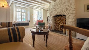 A cozy living room with a stone fireplace, wooden beams, and comfortable seating.