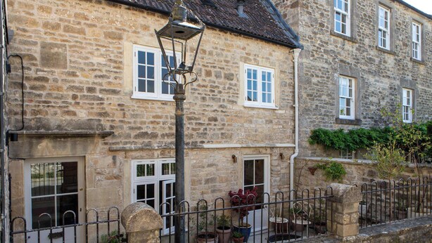 A stone building with multiple windows, a metal fence, and potted plants.