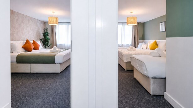 Une chambre d’hôtel avec deux lits, une grande fenêtre et une plante.