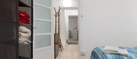 A room with a bed, a wardrobe, and a door leading to another room.
