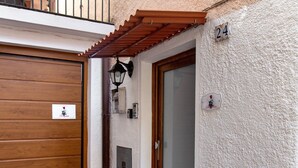 Ein Gebäudeeingang mit Holztür, einem Balkon, einem Schild mit der Nummer 24 und einer wandmontierten Leuchte.