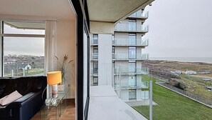 A modern apartment with a balcony overlooking a grassy area and a distant view of buildings. - Flat Neptunus - Amazing seaview in De Panne (De Panne)
