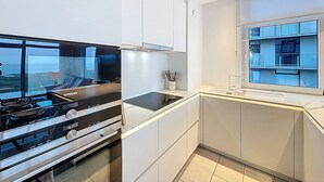 A modern kitchen with a Siemens stove, white cabinetry, and a view of a building through the window. - Flat Neptunus - Amazing seaview in De Panne (De Panne)