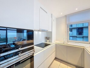 Een moderne keuken met een Siemens fornuis, witte kasten en uitzicht op een gebouw door het raam.