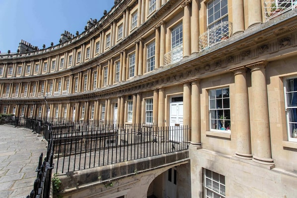 A classical building with a curved facade, large windows, and a stone-paved courtyard.