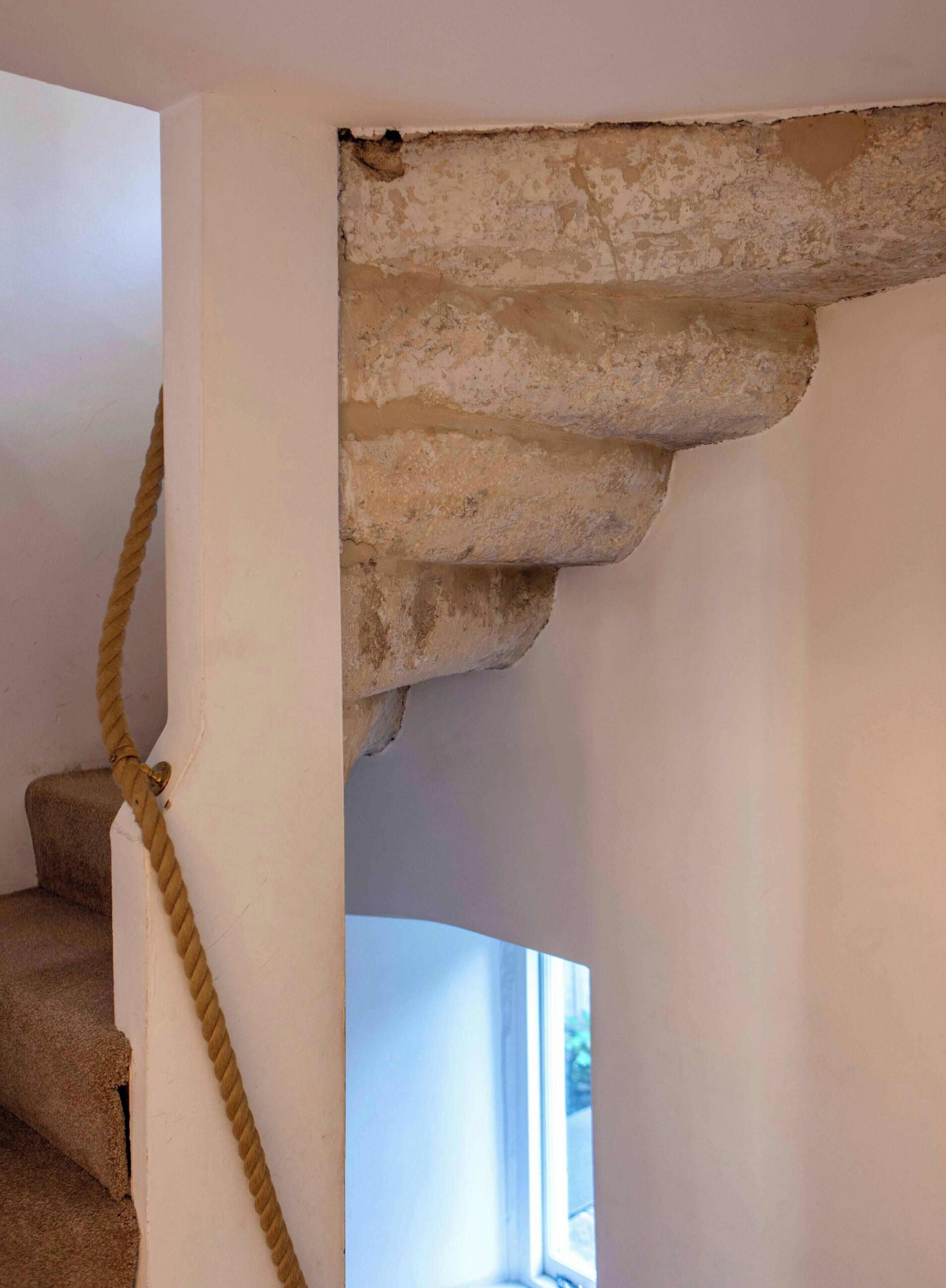 A staircase with a rope handrail and a stone ledge.