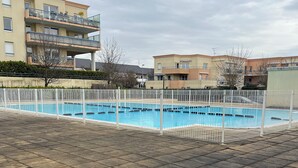 A swimming pool with a white fence, surrounded by a tiled patio area. - Charming T2 near Zenith and Toison d'or, quick access to downtown! (Dijon)