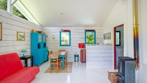 Ein gemütlicher Wohnraum mit einem roten Sofa, einem Holzesstisch, einem blauen Schrank und einem schwarzen Herd.