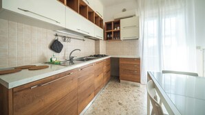 Een moderne keuken met houten kastjes, een wit aanrecht en een glazen eettafel.