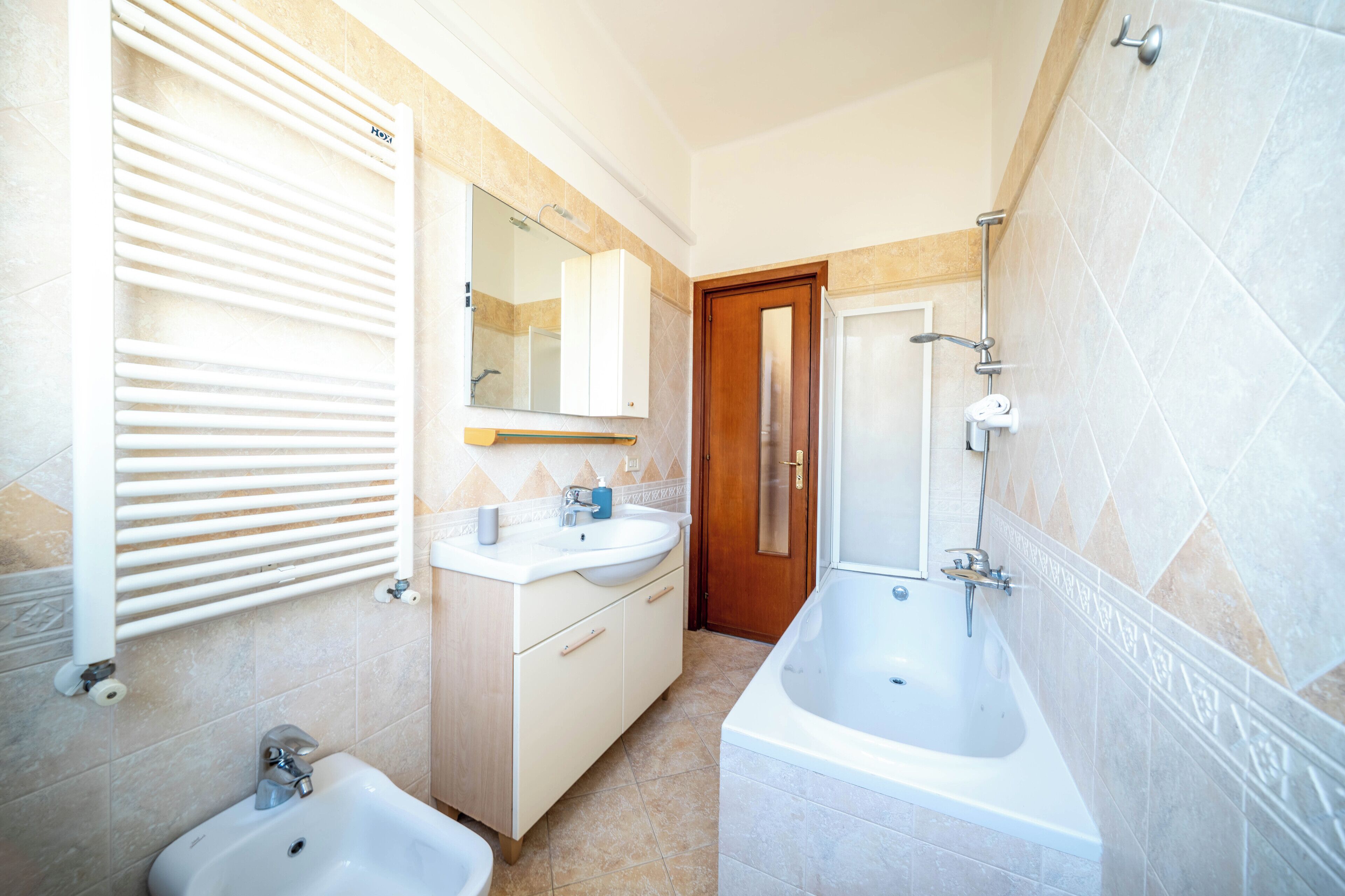 Un baño con dos lavamanos, una bañera, un espejo y un perchero para toallas.