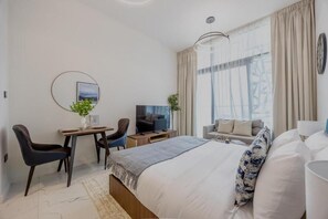 Ein modernes Hotelzimmer mit einem großen Bett, einem Schreibtisch mit Stuhl, einem Fernseher und einer Sitzecke.