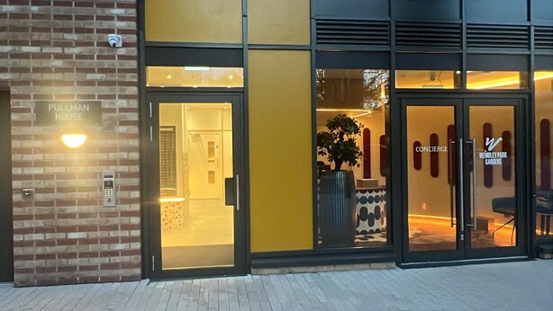 En hotelindgang med glassefterdør, et indblik i indretningen, og et skilt med teksten "Pullman House".