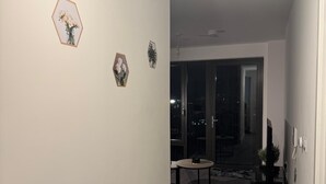 En gang med et rundt bord, stole, en potteplante og billedkunst på væggene.