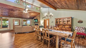 A spacious living area with a dining table, wooden chairs, and a high ceiling with exposed beams. - Scenic Serenity | Maggie Valley, 4BR, 3 BA, VIEWS! (Maggie Valley)