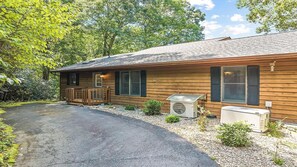 A wooden cabin with a gravel driveway, a covered porch, and two air conditioning units. - Scenic Serenity | Maggie Valley, 4BR, 3 BA, VIEWS! (Maggie Valley)