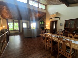 Uma sala ampla com uma mesa de jantar de madeira, cadeiras, um sofá e uma lareira de pedra.