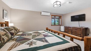 A bedroom with a bed, a dresser, a television, and a window with a view of trees. - Scenic Serenity | Maggie Valley, 4BR, 3 BA, VIEWS! (Maggie Valley)