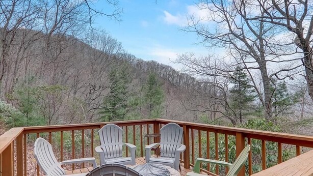 Una terrazza con poltrone Adirondack e un tavolo, affacciata su una zona boschiva.
