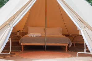 Ein Zelt mit Bett, Kissen und einem kleinen Tisch mit Lampe.