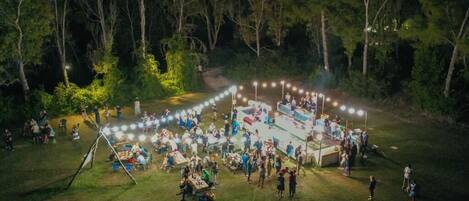 An outdoor event with a circular arrangement of tables and chairs, surrounded by trees.