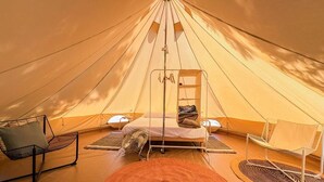 Une tente équipée d’un lit, de deux chaises et d’un ventilateur.