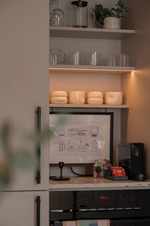Eine Küche mit Kaffeemaschine, einer gerahmten Speisekarte und einer digitalen Uhr.