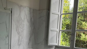 A bathroom with a bidet, toilet, and bathtub. There is a window with a view of greenery outside. - Tintoretto Superior Apartment in historic Villa near Lucca (Matraia)