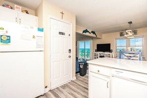 A kitchen with a refrigerator, a sink, and a dining area with a table and chairs. - A Porpoiseful Life - Oceanfront 4 BR Duplex, 2 Decks and Dog Friendly! (N. Topsail Beach)