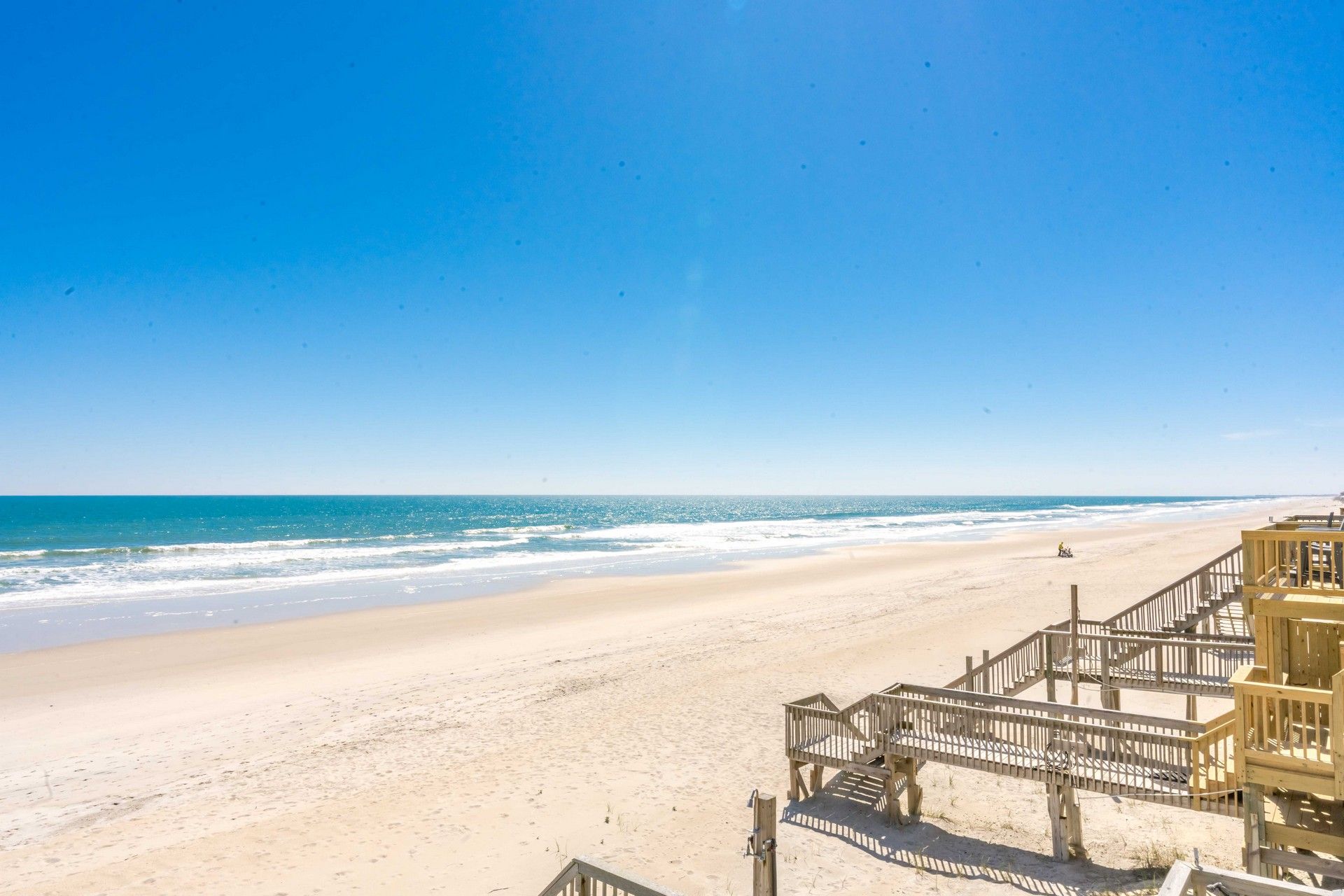 Une plage avec une promenade en bois qui mène à un bâtiment à plusieurs étages.