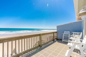 Une terrasse en bois offrant une vue sur la plage et l’océan.