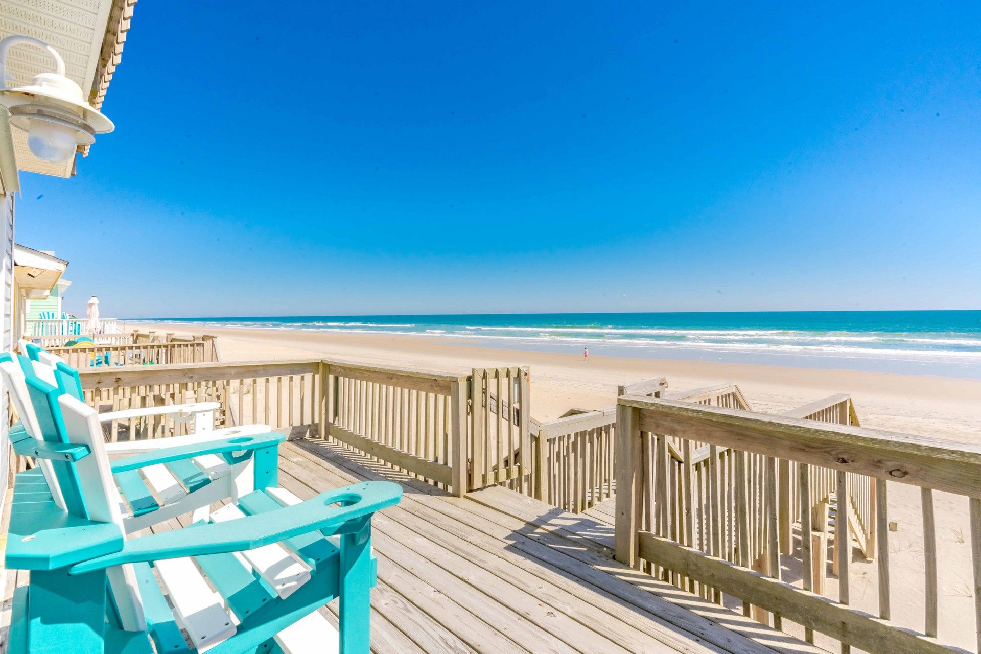 Une terrasse en bois offrant une vue sur la plage et l’océan.