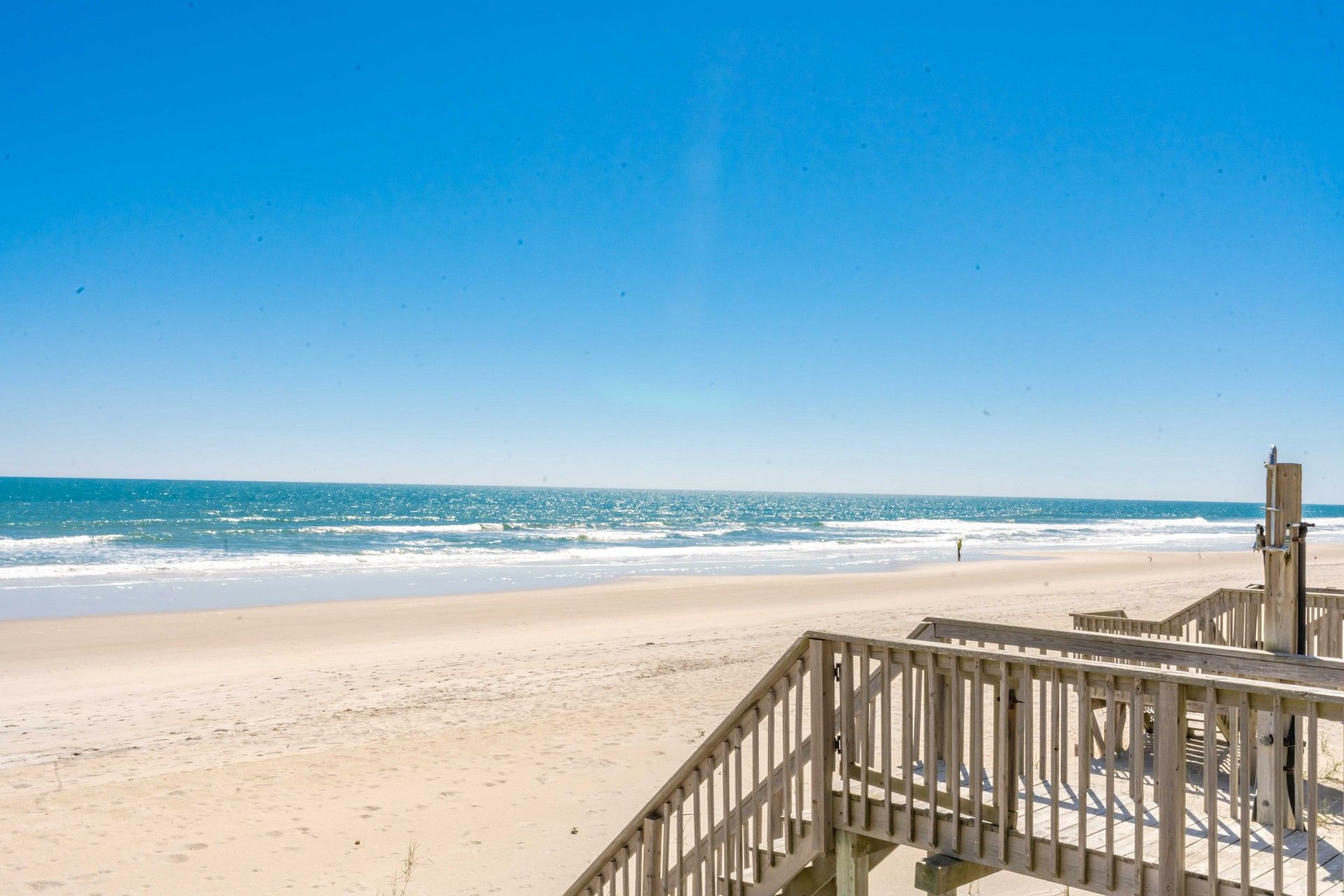 A beach with a wooden walkway leading to the water.