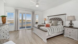 Een slaapkamer met een bed, nachtkastjes, een dressoir, een plafondventilator en uitzicht door een glazen deur.