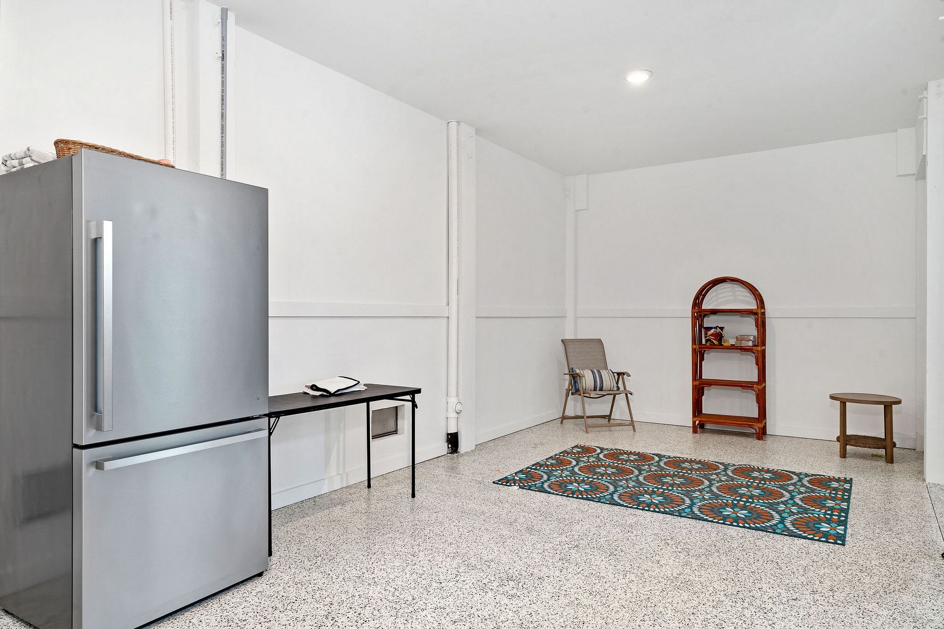 A compact kitchen with a refrigerator, a small table, and a chair.