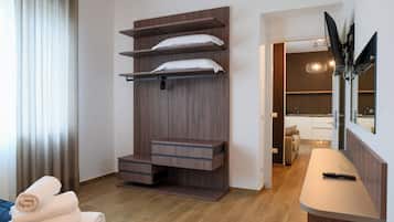 A modern hotel room with a built-in wardrobe, a flat-screen TV, and a small seating area.