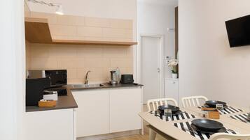 A compact kitchen with a built-in stove, a sink, and a dining area with a table set for four.