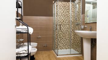 A bathroom with a glass-enclosed shower, a white sink, and a towel rack with folded towels.