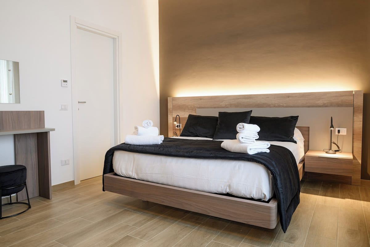 Een moderne hotelkamer met een groot bed, nachtkastjes, een bureau en een stoel.
