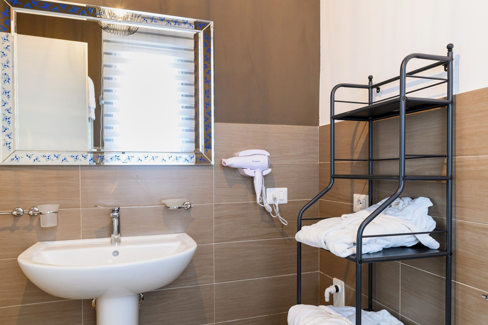 A bathroom with a sink, mirror, towel rack, and a hairdryer.
