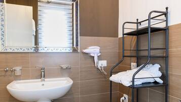Ein Badezimmer mit Waschbecken, Spiegel, Handtuchhalter und einem Fön.